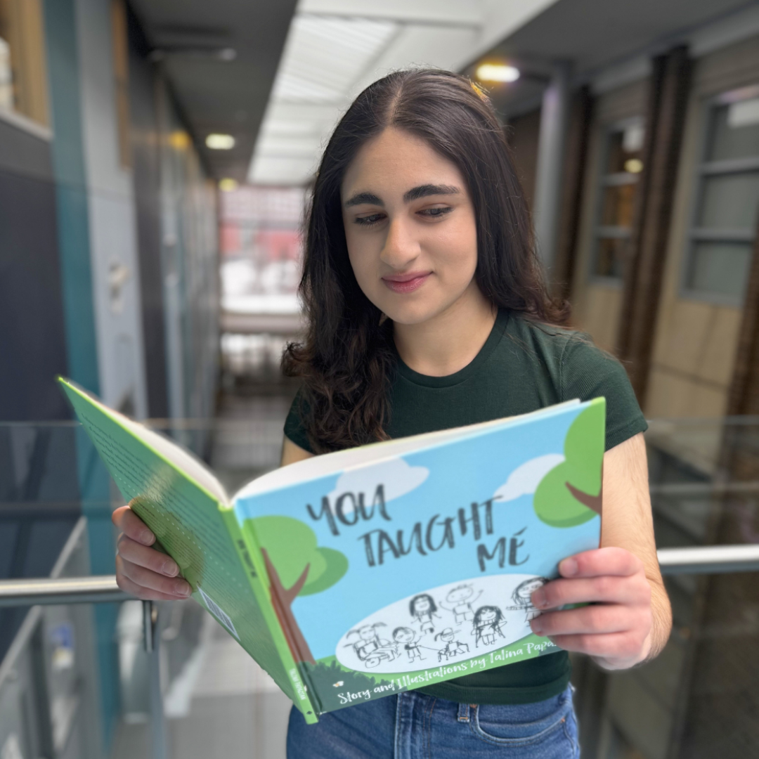 Talina holding her book "You Taught Me"