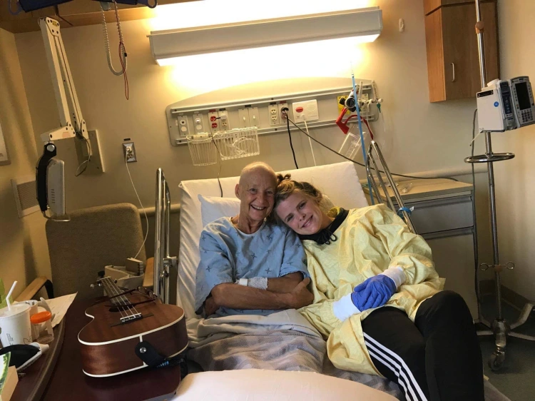 Director of TAMVOES, Jordan Lunshof, laying in a hospital bed with her grandmother