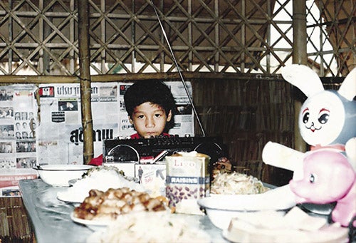 A young Vin Nguyen looking mournful at his birthday party in a tent in a refugee camp