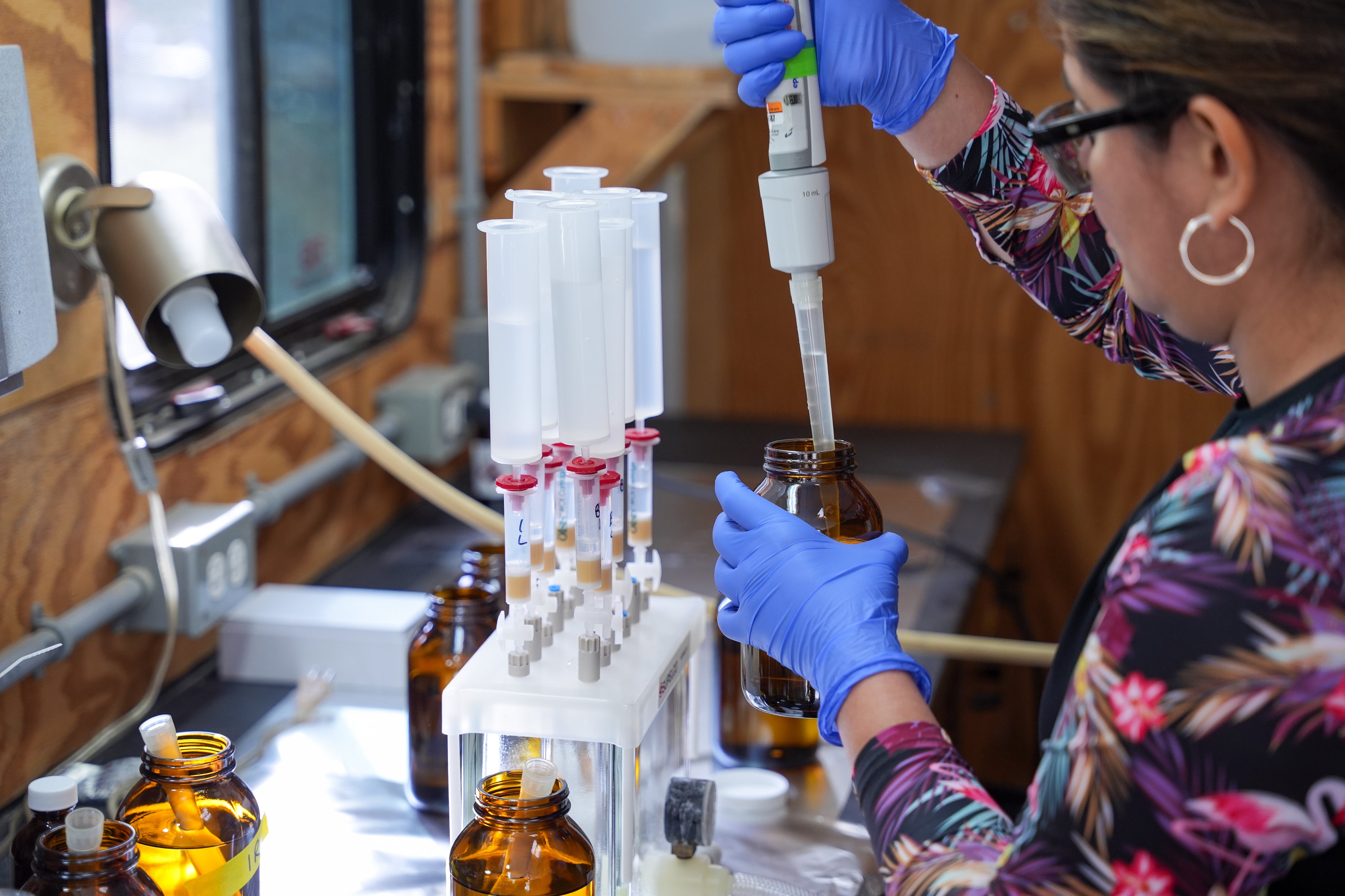 Woman in lab pouring liquid into a jar