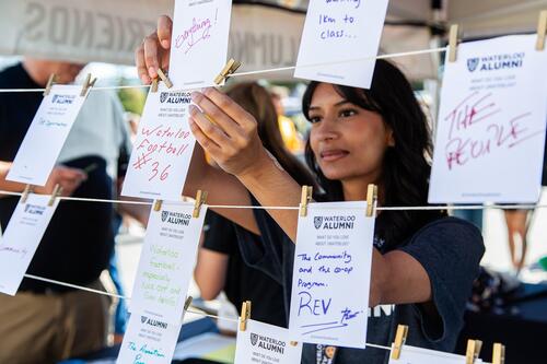 A student hangs up cards saying what people love about Waterloo