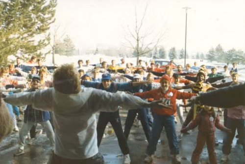 Participants warm up, standing with their feet wide and arms out