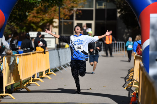A man holds his arms out in relief as he crosses the finish line