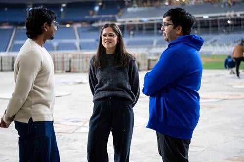 Gabrielle Campus chats with fellow alumni Khalid Talakshi and Josh Poozhikala while standing on the field at Rogers Centre