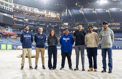 Group of Waterloo alumni pose together on the field at Rogers Centre