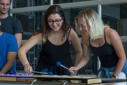 Two students play an electric marimba together