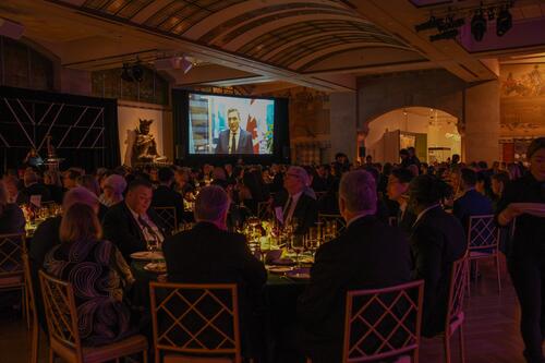 Dinner event guests seated at round tables, filling a museum atrium