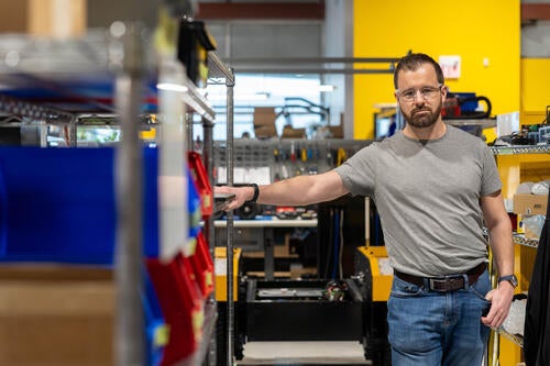 Ryan Gariepy leans against some shelves inside a Clearpath warehouse