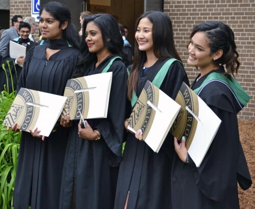 Recent graduates holding their degrees.