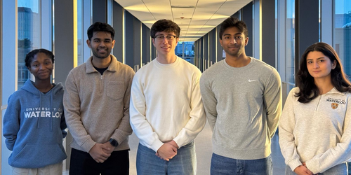 Four students pose on a pedestrian bridge at the University of Waterloo.