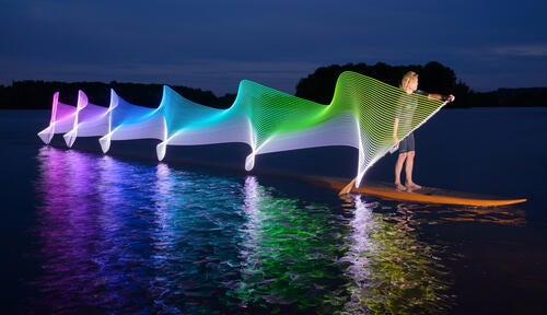 A paddleboarder at night with a paddle covered in LEDs, photographed by Stephen Orlando