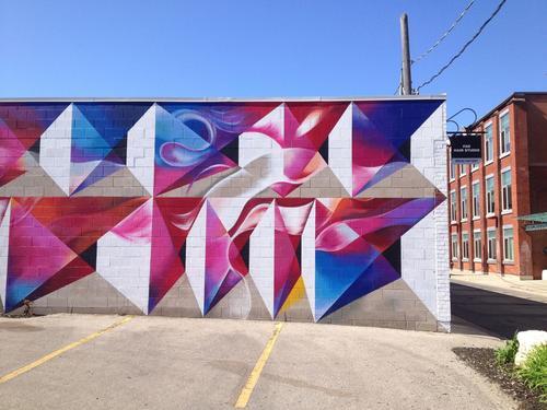 Stephanie's first mural on the outside wall of the Bread Factory located across from Waterloo’s School of Architecture with waves and clouds of blue, pink, and purple encased in geometric shapes. 