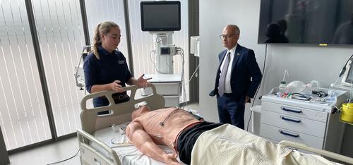 A researcher is showing President Vivek Goel tests being done on a mannequin in a hospital bed.