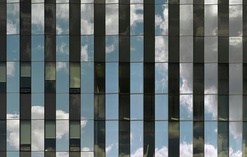 Glass wall of Institute for Quantum Computing reflecting clouds in the sky