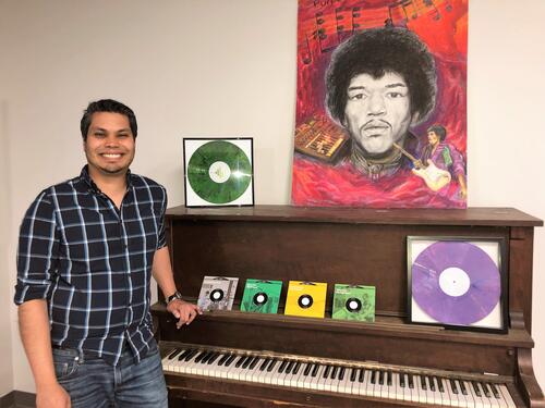James Hashmi poses with the office piano, one of his paintings and some of the records that have been pressed at Viryl Technologies in Toronto.
