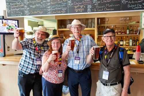 Four alumni holding beer glasses up for a cheers