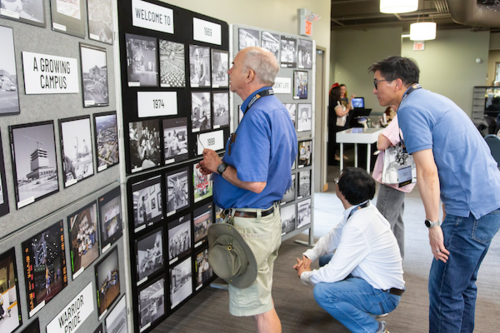 Alumni looking at a display of photos from the archives