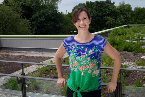Sarah Burch posing next to an environmentally friendly roof