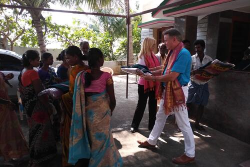 Michael and Stacey hand blankets to a group of women wearing saris