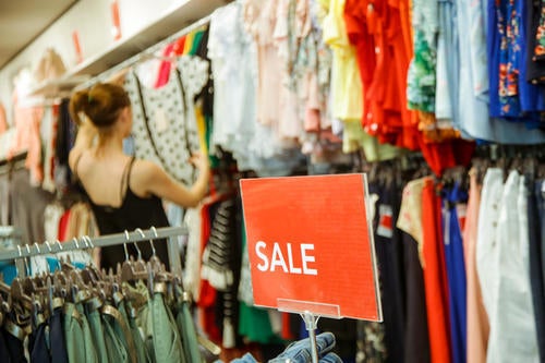 A woman shops for clothes, which are marked on sale.