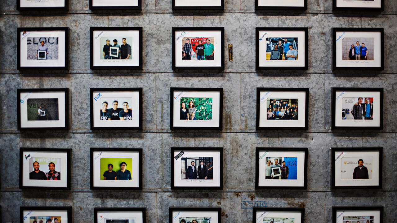 Framed photos of Velocity companies cover a brick wall