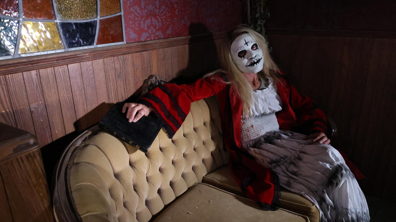 Meghan Snyder wearing a Halloween costume sitting on an antique couch inside one of Snyder's Farm's haunted houses