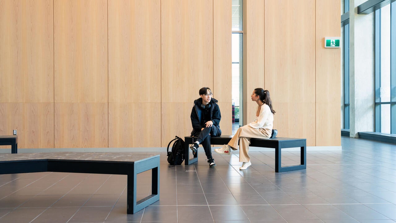 two students talking on a bench