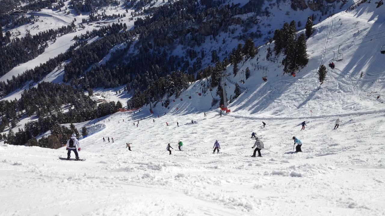 Scene of skiers and snowboarders on the snow with mountain in background