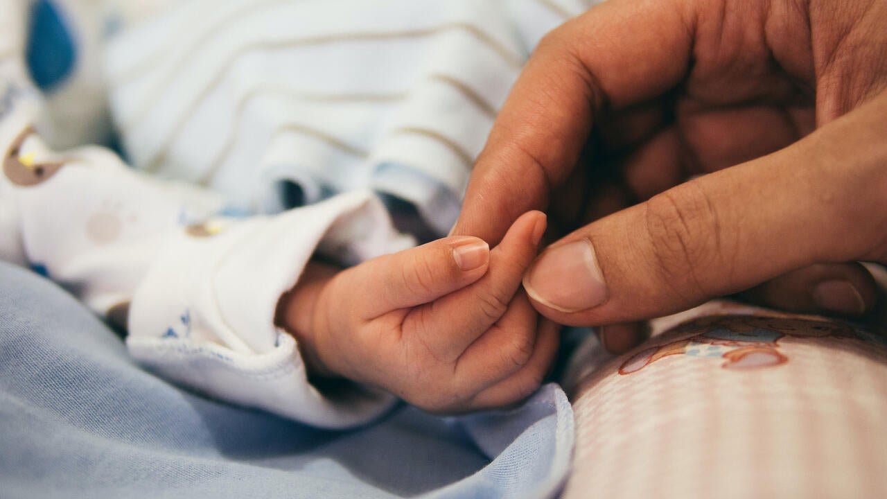 baby hand holding an adult hand