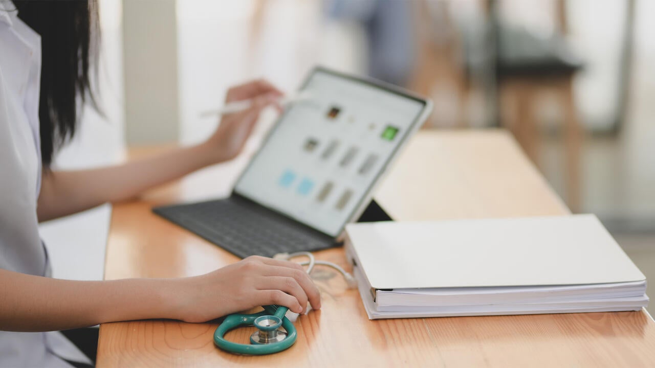 Medical professional using an electronic device to check a patient's charts