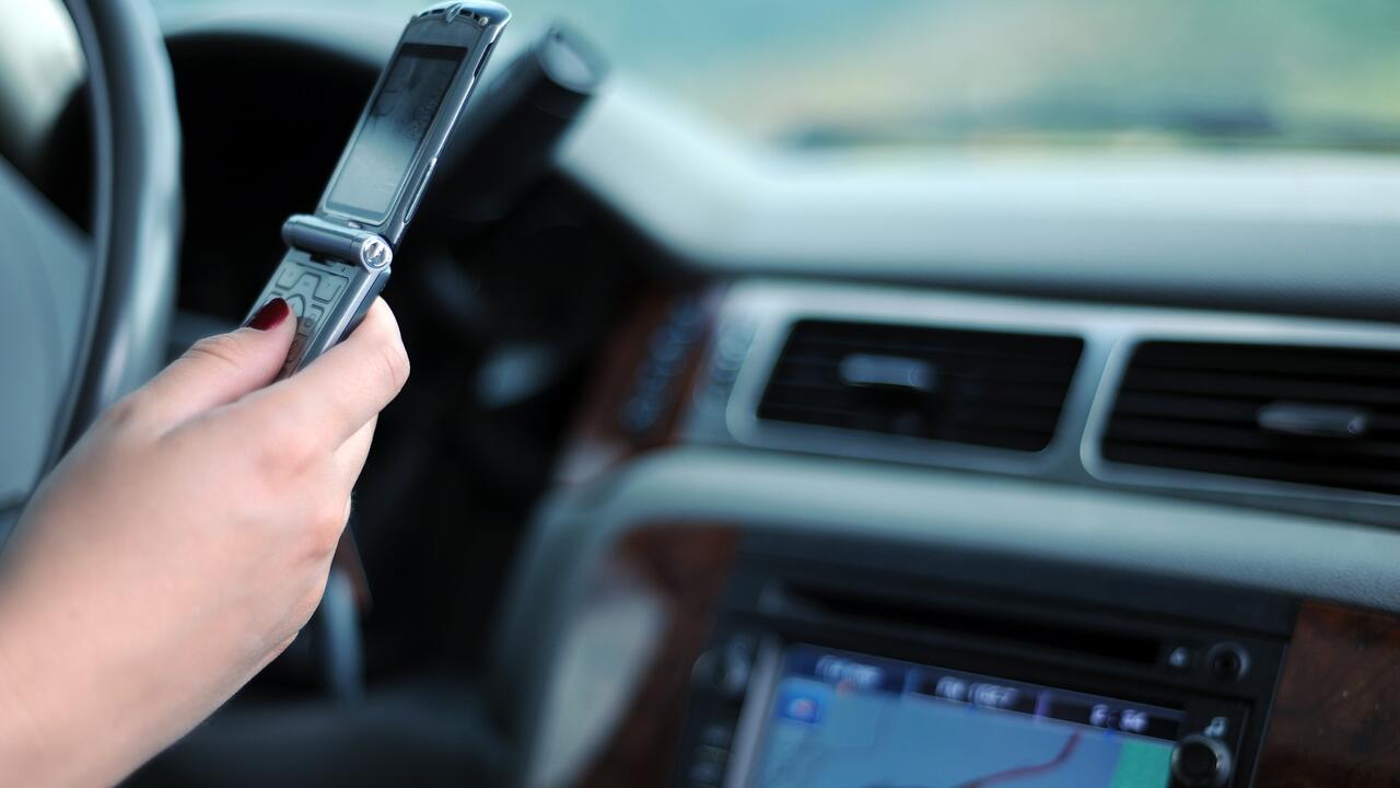 Image of hand holding a phone while driving