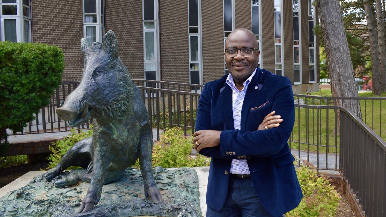 Dr Alexie Tcheuyap with sculpture of boar on campus