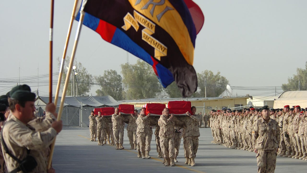 Rows of soldiers standing by while caskets pass by