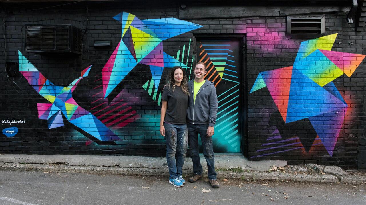 Stephanie Boutari and Adam Schwartzentruber in front of a mural