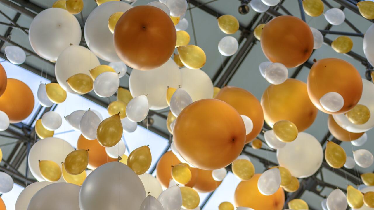 gold and white balloons float into the sky