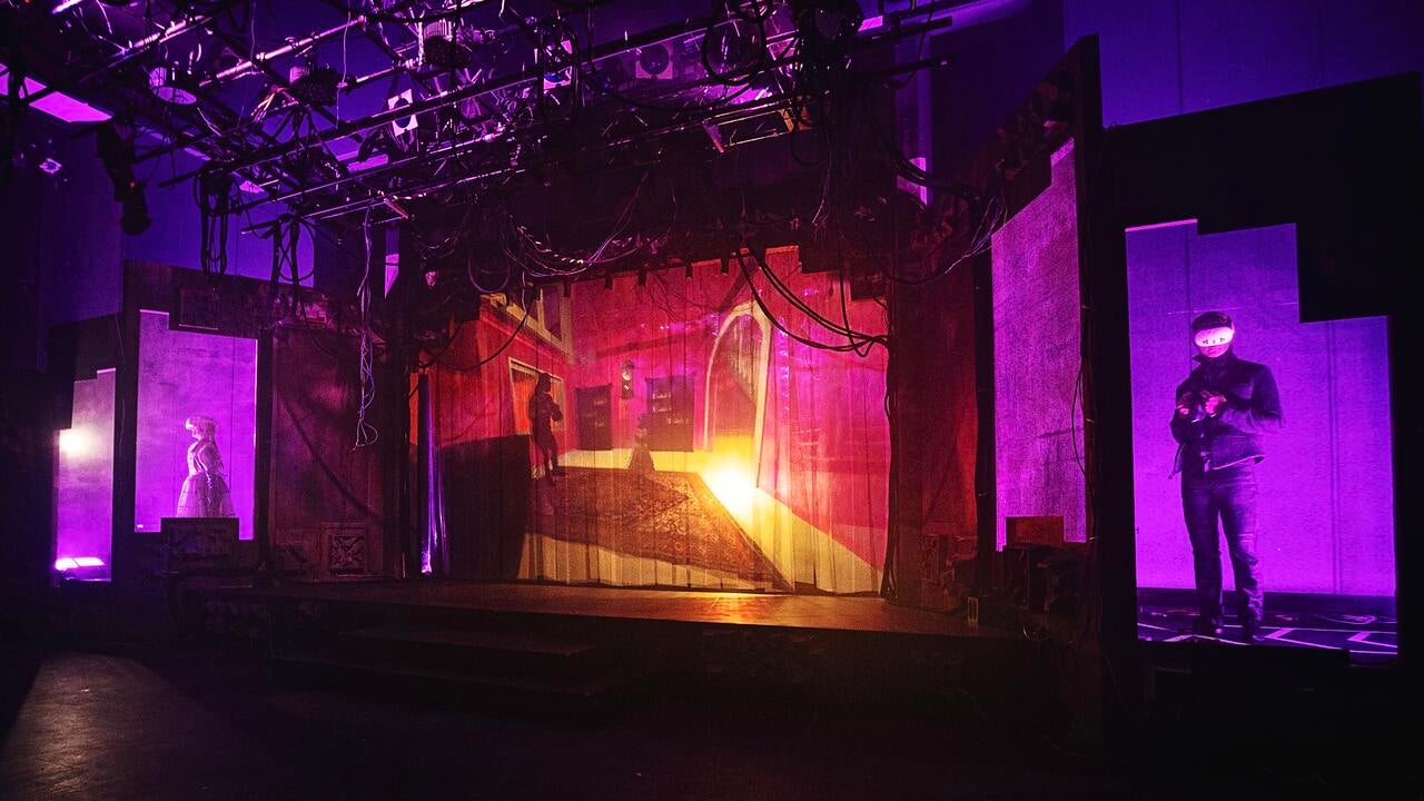 Stage with actors in VR headsets and screen showing their avatars