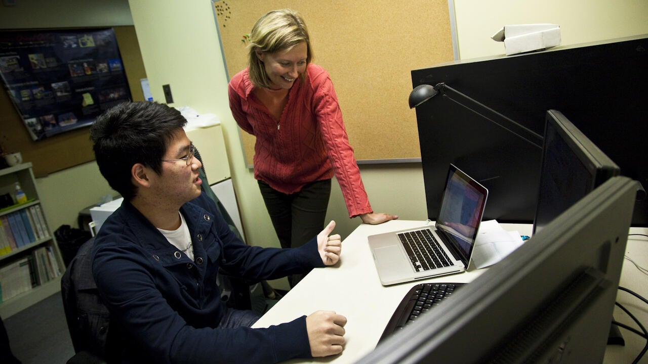 Catherine Burns looking at a computer with a student 