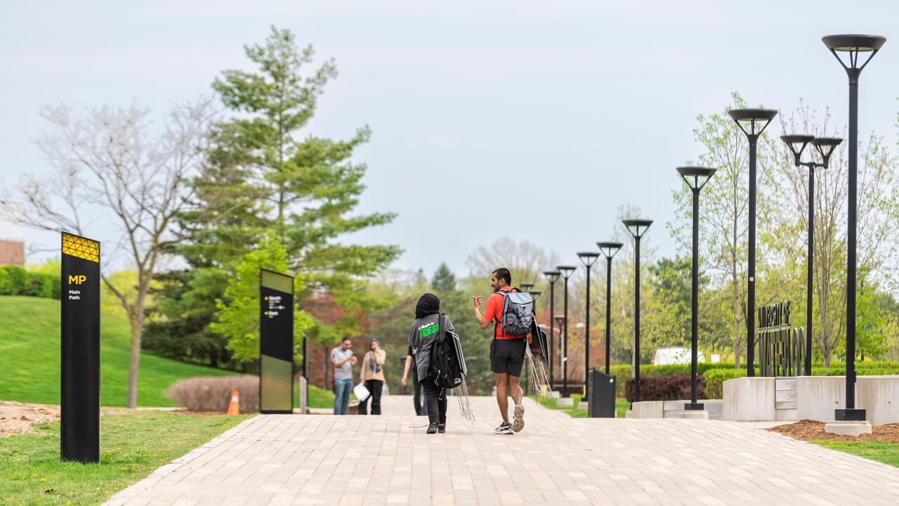 Two students walk down a path on campus