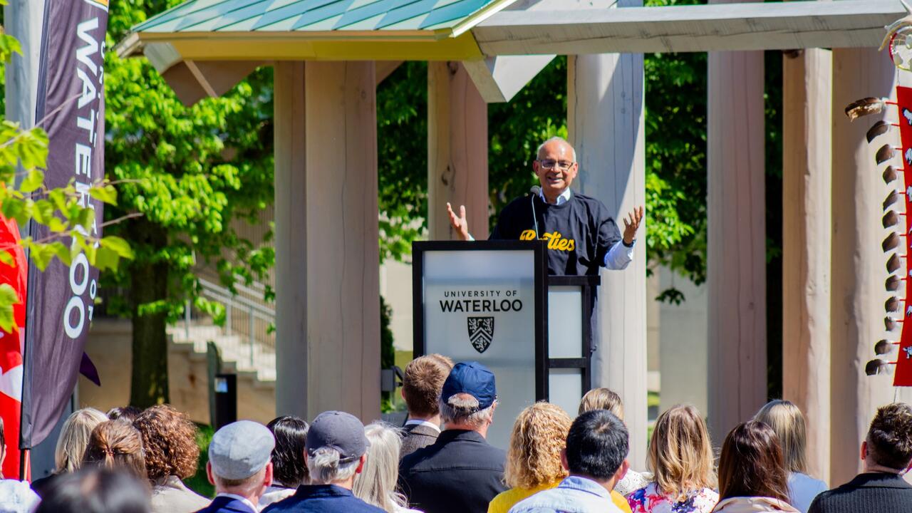 President Vivek Goel addresses a crowd from a podium outside the Indigenous Gathering space on campus