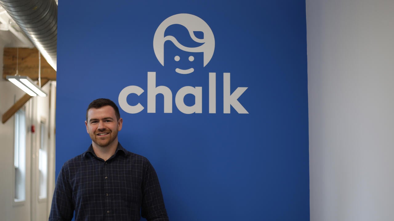 Kynan Gallagher in front of his company logo