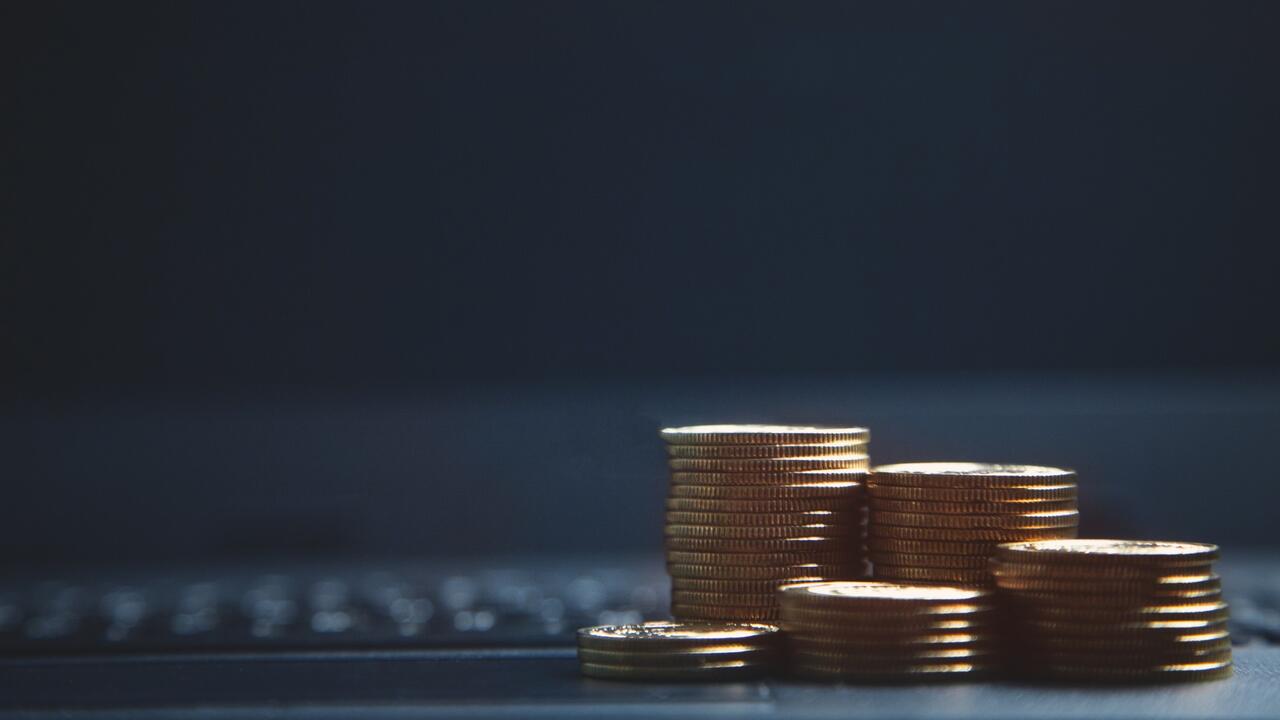 Stacks of coins in front of a computer keyboard