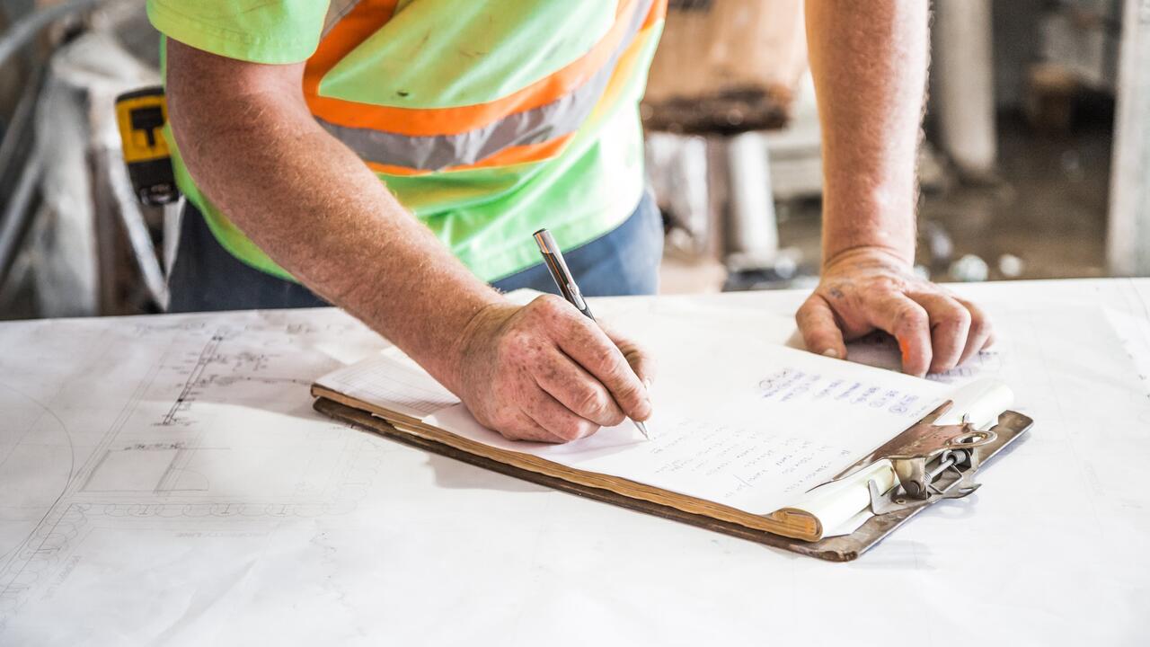 A construction worker writing on a clipboard