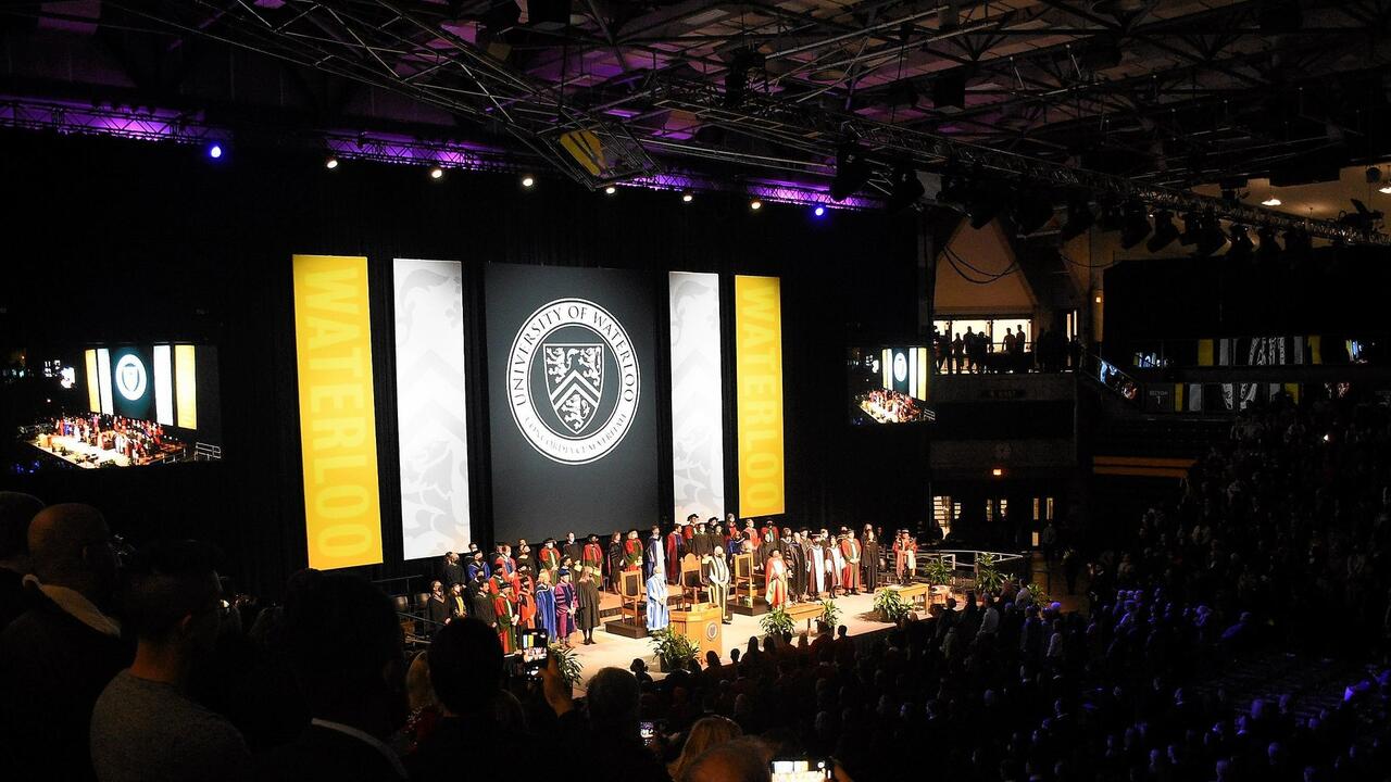 Convocation stage with dignitaries standing and recognizing the crowd
