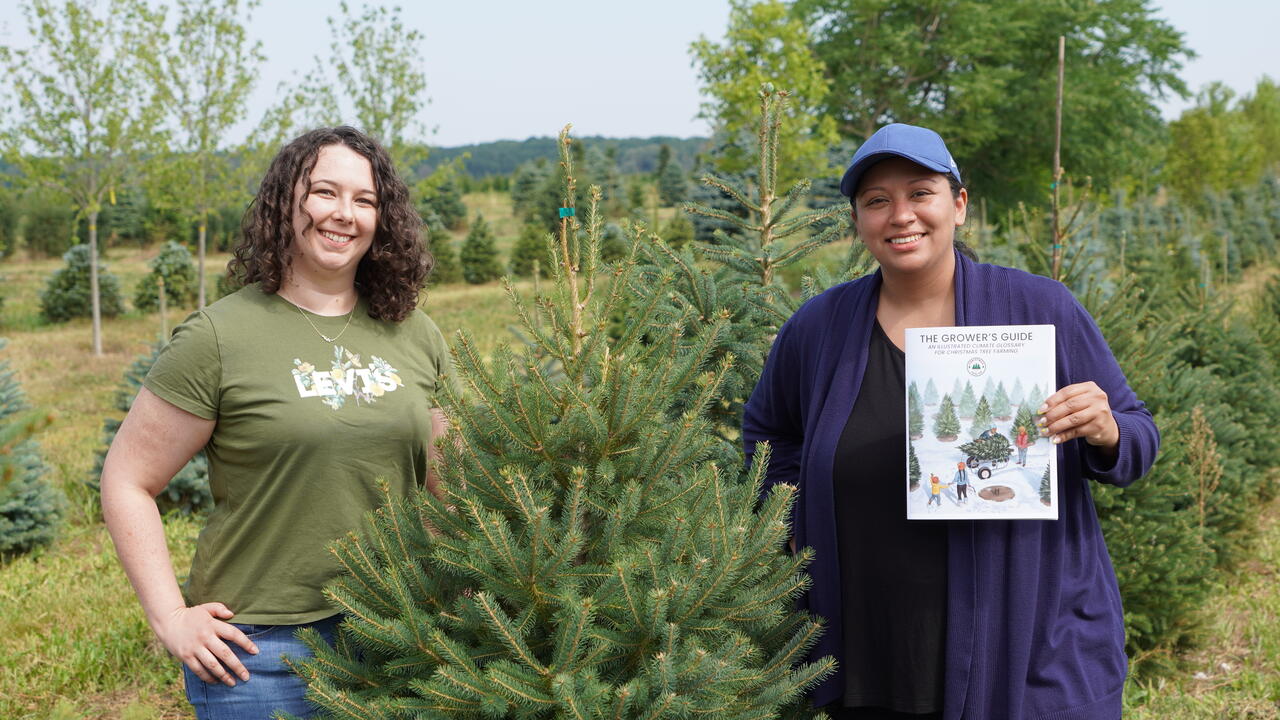 Two women standing beside a chirstmas tree. 