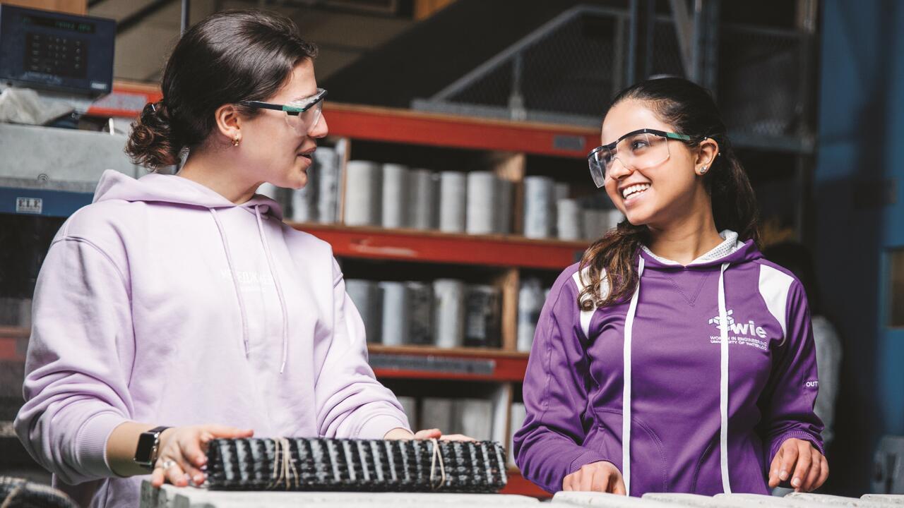 Two female students smiling at each other with goggles on at a lab