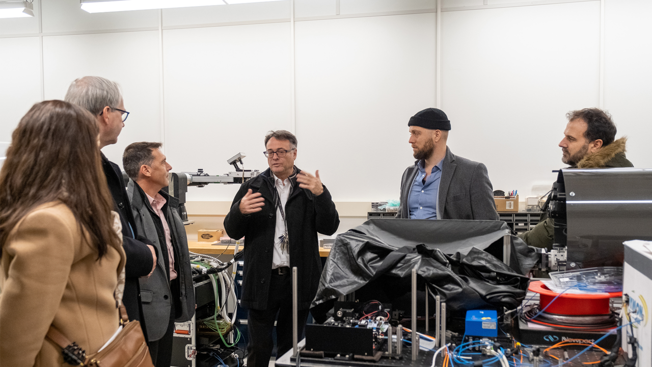 Thomas Jennewein explaining equipment in his lab to five other people