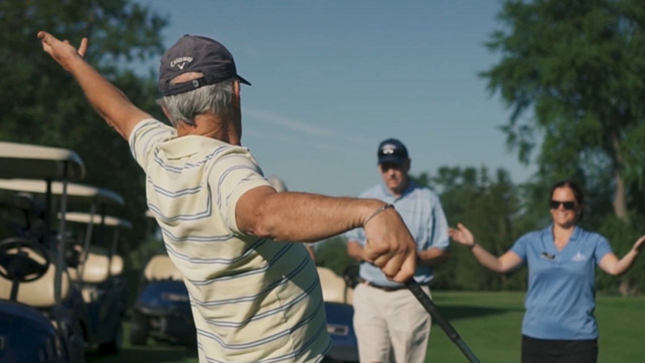 Older man celebrating with others on a golf course