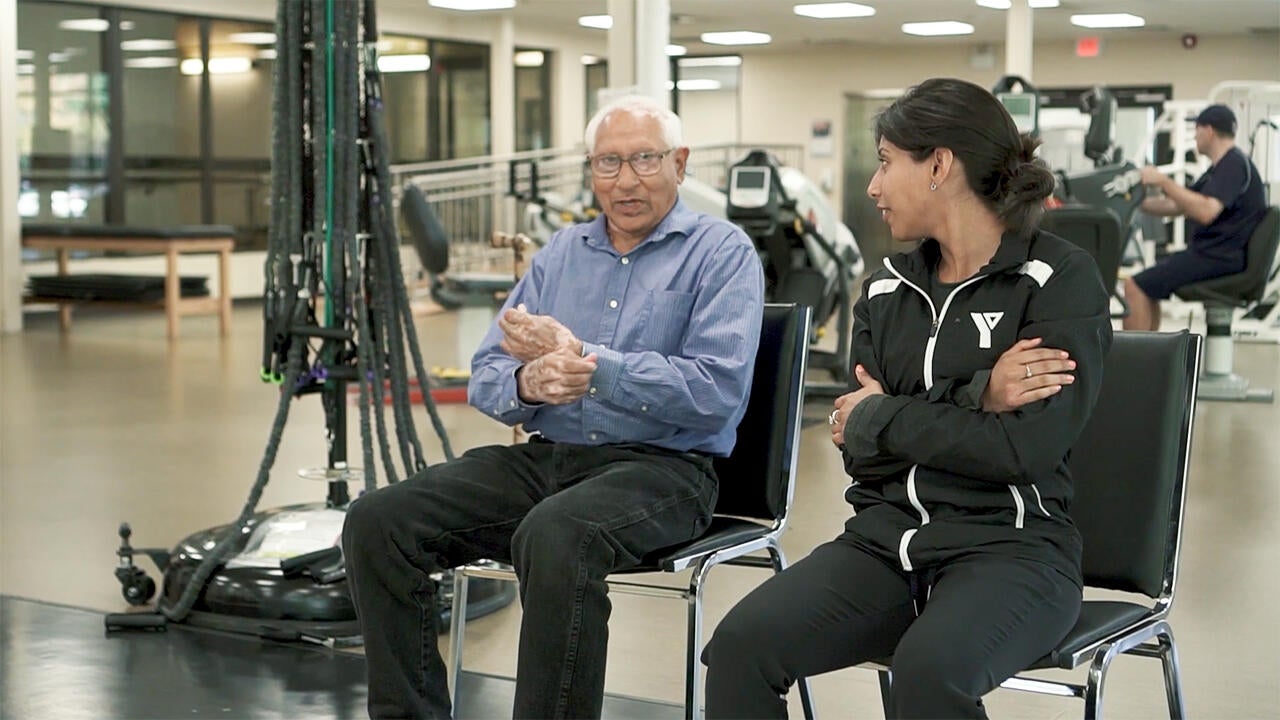 Older person and trainer in gym setting