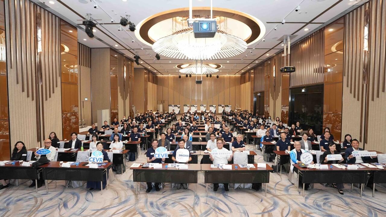 A large group of researchers sitting together at desks in a meeting room