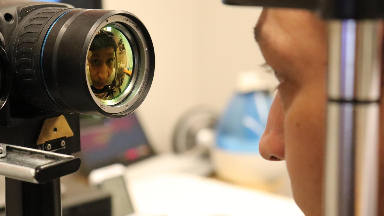 A selfie reflection of a researcher looking into a eye testing equipment